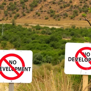 Nature landscape with "No Development" signs in foreground.